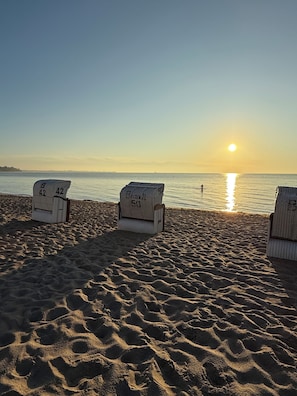 A beach with three sun loungers, each with a number on it.