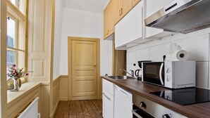 A compact kitchen with white cabinets, a wooden countertop, a microwave, a kettle, and a sink. - Charming Apartment in Old Town (Stockholm)