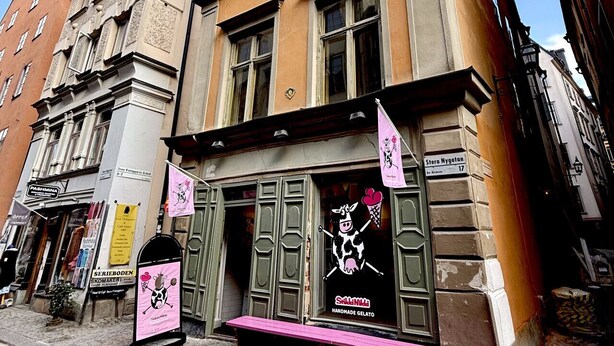 A building with a shop on the ground floor, a sign for 'Stora Nyhagen' on the right, and a pink banner advertising 'Sall Nils Handmade Gelato'. - Charming Apartment in Old Town (Stockholm)
