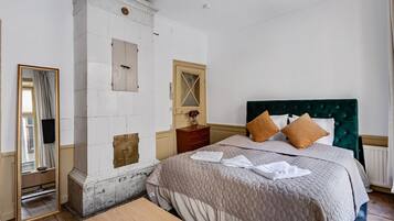 A hotel room with a large bed, a wooden dresser, a mirror, and a white wardrobe.
