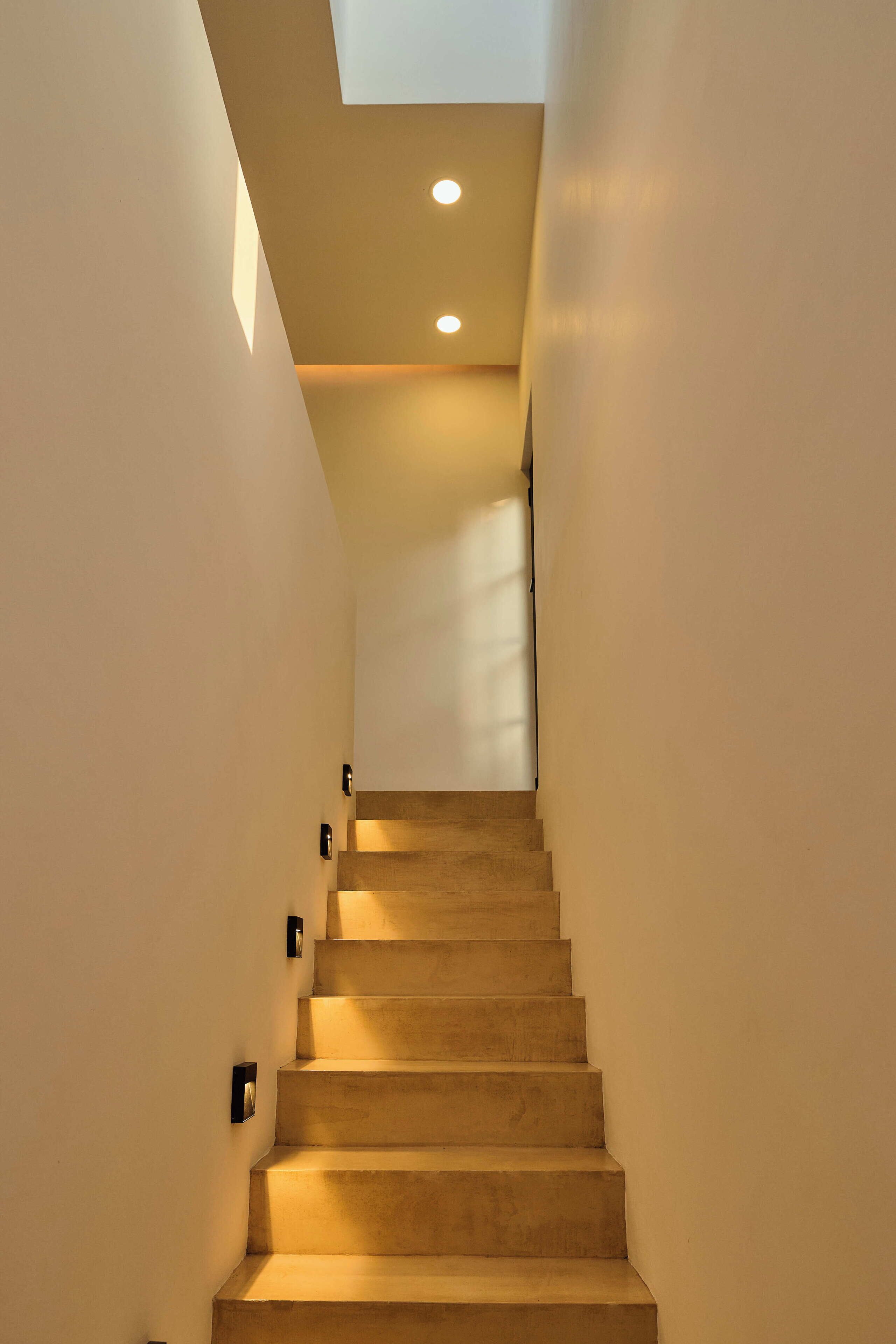 A staircase with a modern design, recessed lighting, and a view of the upper floor.