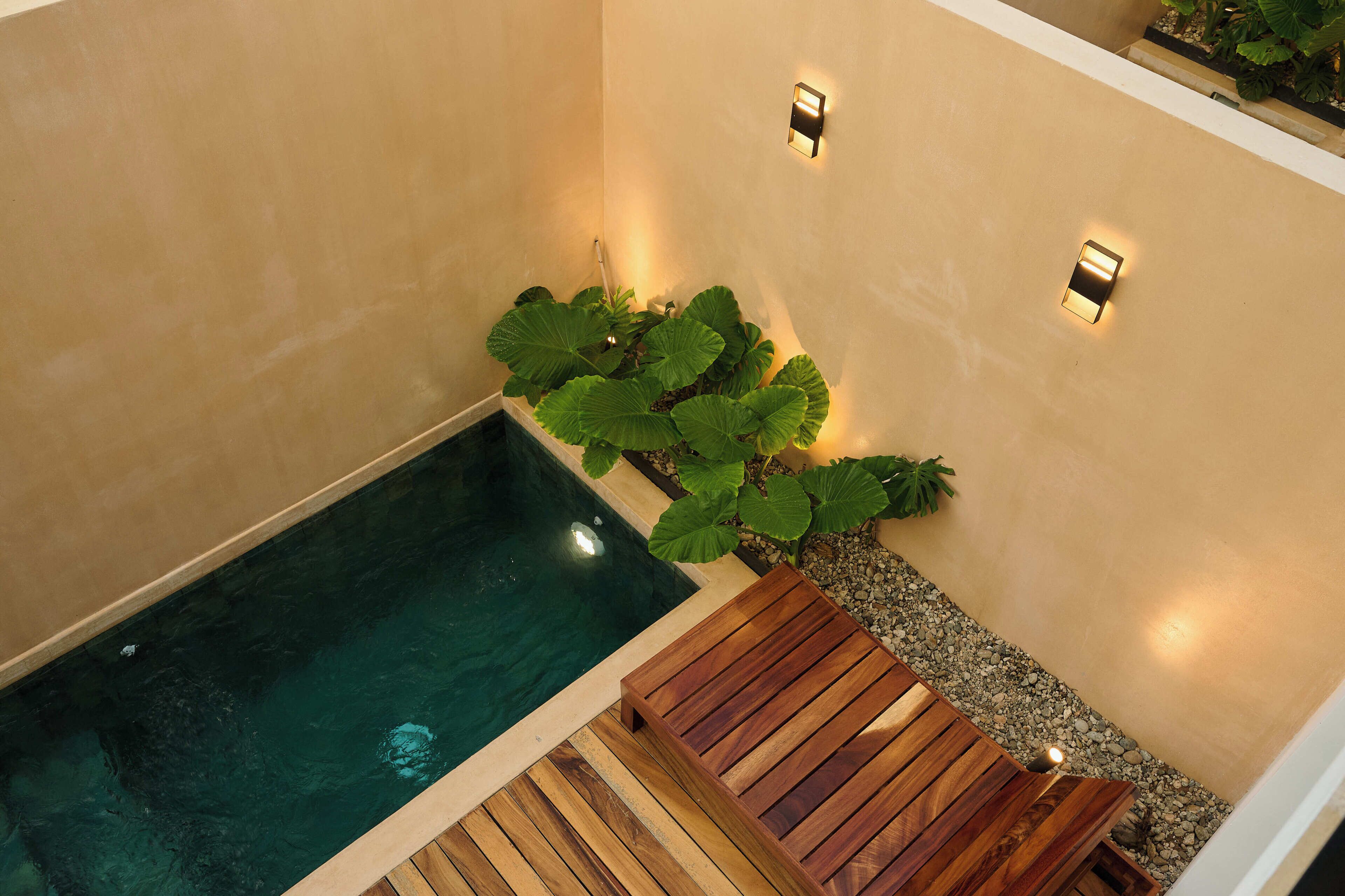 A spa area with a hot tub, wooden deck, and wall-mounted lights.