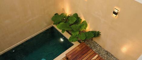 A spa area with a hot tub, wooden deck, and wall-mounted lights.