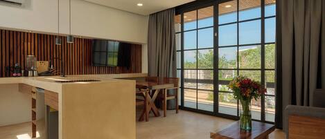 A modern kitchen with a central island, dining area with wooden furniture, and large windows with curtains.