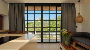 A modern kitchen with a large window, a dining area, and a seating space. - Hotel Compatir (Santa María Colotepec)