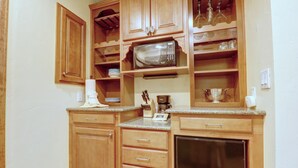 Una cocina compacta con armarios de madera, microondas, refrigerador y cafetera.