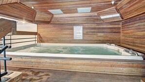 Un spa con sala de madera que incluye una bañera de hidromasaje, paredes de madera y un letrero de precaución.