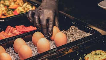 Une personne portant un gant noir dépose des œufs sur un plateau.