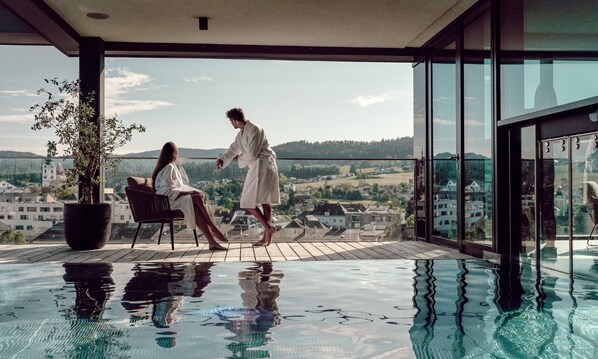 Alberca techada, alberca al aire libre y sombrillas en la alberca