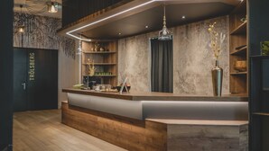 A modern reception area with a wooden counter, a coffee machine, and decorative plants. - Hotel FREIGOLD (Freistadt)