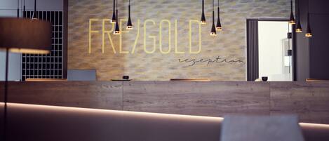 A reception area with a wooden reception desk, pendant lighting, and a wall with the text "FREE/GOLD reception".