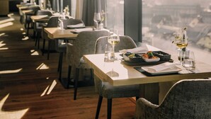 A restaurant with tables set for dining, large windows, and a view of the city. - Hotel FREIGOLD (Freistadt)