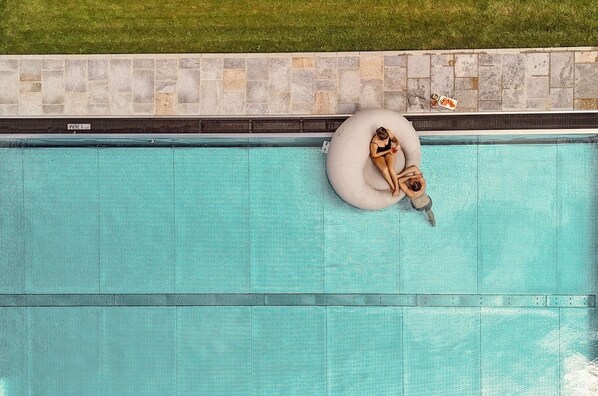 Una piscina techada, una piscina al aire libre, sombrillas
