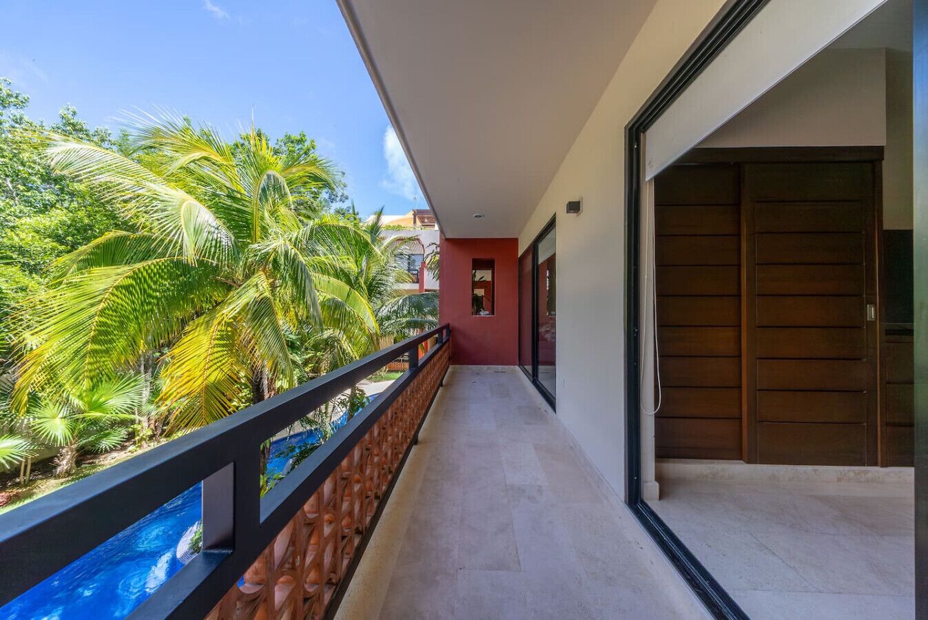 Un balcón con vistas a palmeras y una piscina.