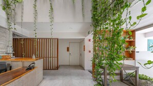 Een modern interieur met een receptiebalie, houten scheidingswanden en hangplanten.