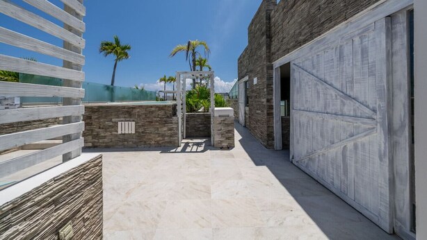 Een modern gebouw met een gevel van natuursteen, een houten pergola en een helderblauwe lucht.