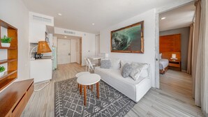 Een moderne hotelkamer met een witte bank, een eettafel en een groot abstract schilderij.