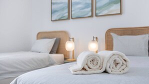 A hotel room with two beds, each with a headboard and pillows. There are two wall-mounted lamps on either side of the beds. - Casa Gio Apartment - Praia da Luz (Luz)
