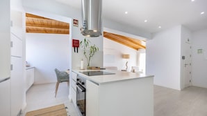 A modern kitchen with white cabinetry, a central island, and a wooden ceiling. - Casa Gio Apartment - Praia da Luz (Luz)