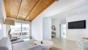 A modern living room with a sofa, coffee table, and TV. There is a balcony with outdoor furniture. - Casa Gio Apartment - Praia da Luz (Luz)
