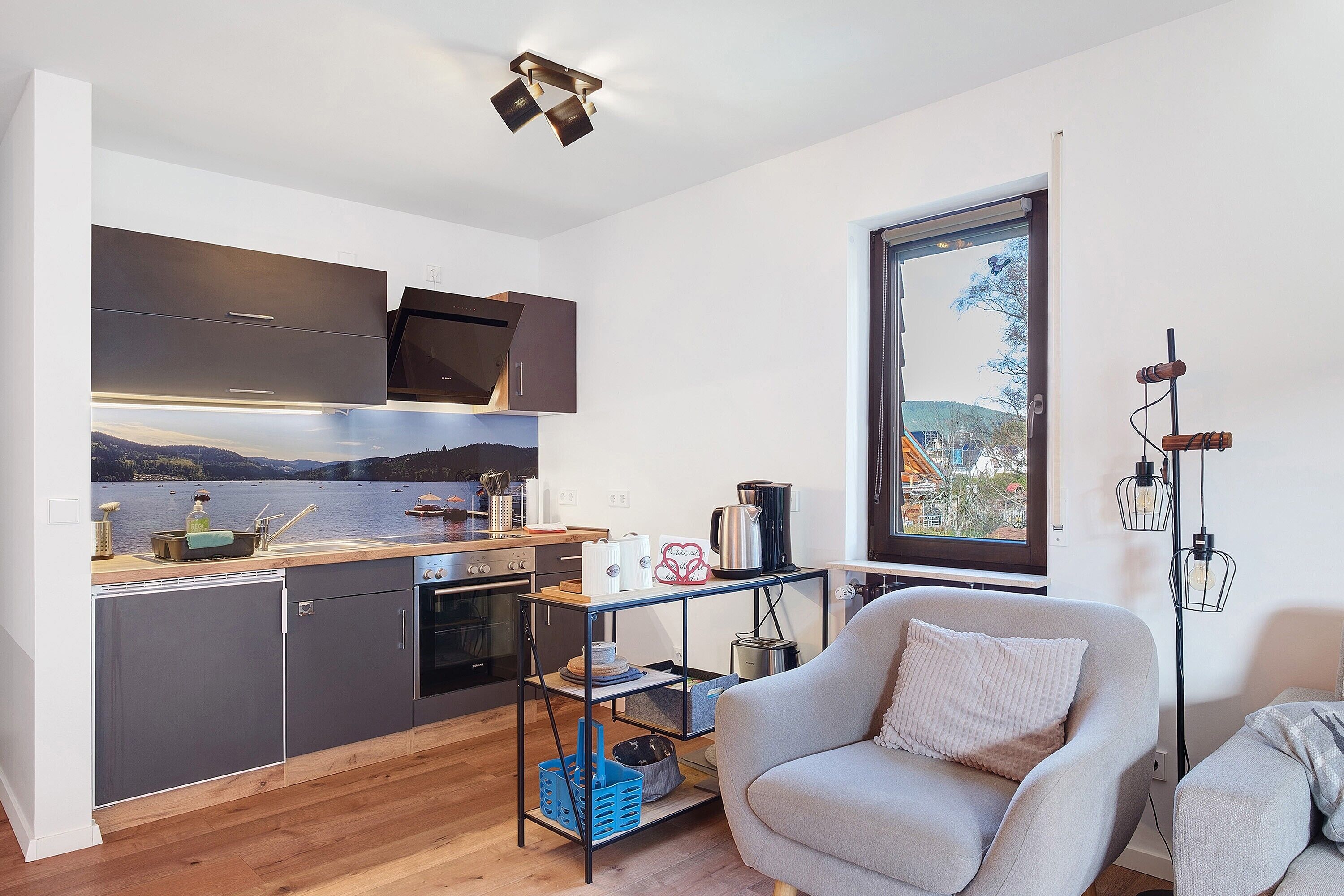 Eine moderne Küche mit Seeblick, ein Essbereich mit einer Couch und einer Stehlampe.