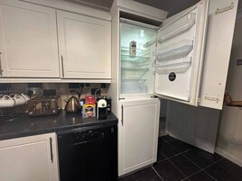 A compact kitchen with white cabinets, a dishwasher, a toaster, a kettle, and a coffee maker.