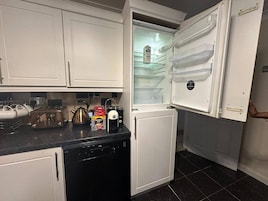 A compact kitchen with a built-in dishwasher, a coffee maker, and a Nespresso machine on the counter.