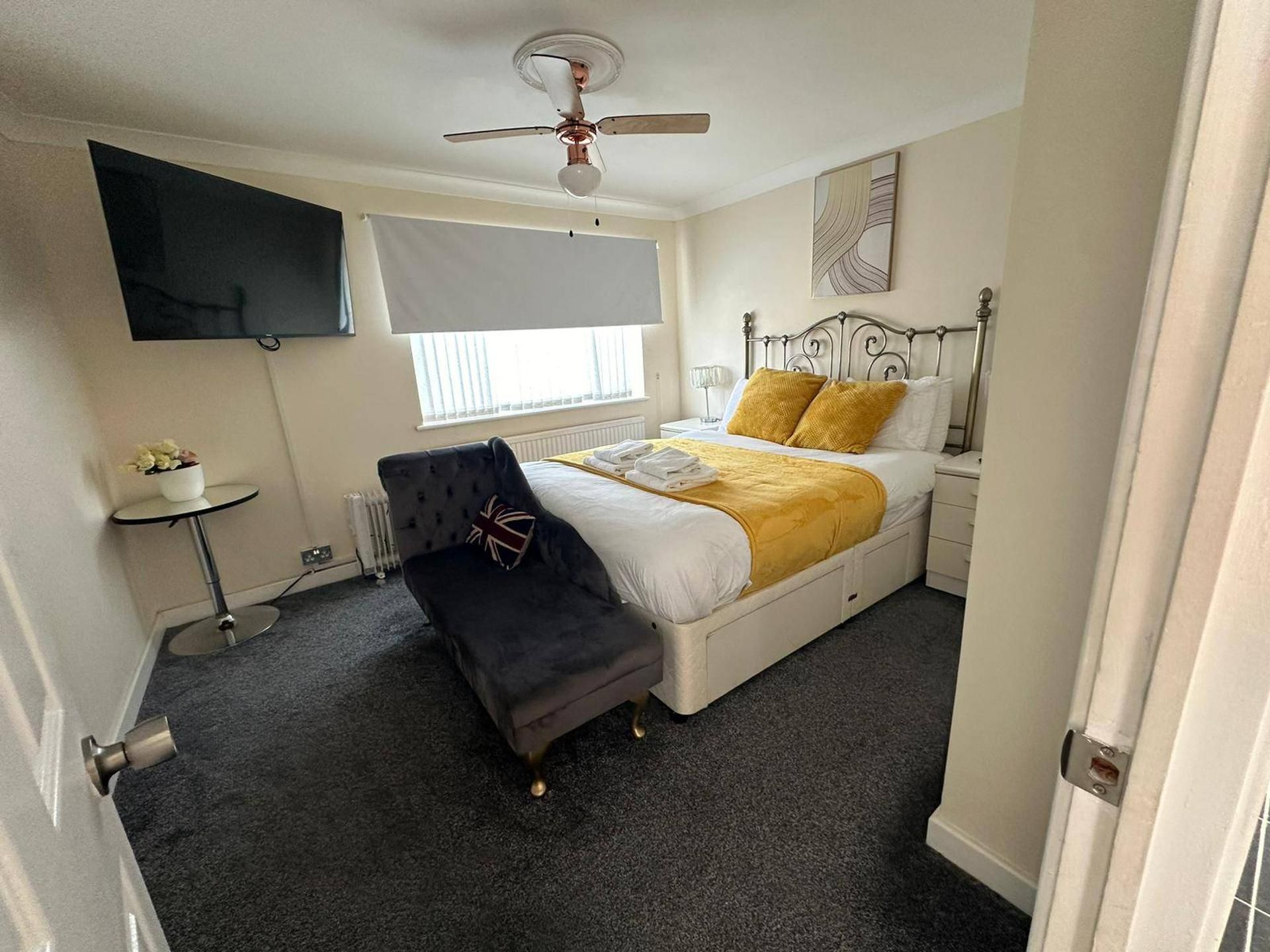 Ein Hotelzimmer mit einem Bett, einem Schreibtisch, einem Sessel, einem Fernseher und einem Deckenventilator.