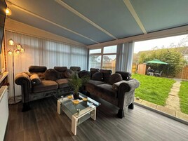 A modern living room with a large sectional sofa, a glass coffee table, and a view of the backyard.