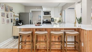 Uma cozinha moderna com uma ilha grande, banquetas de bar e vista para a área de refeições.