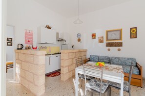 Un espace de vie compact comprenant un coin cuisine, un coin repas et un coin salon.