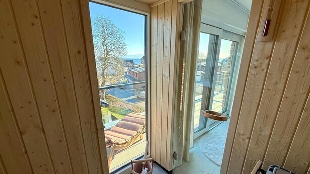 Interior em madeira com uma grande porta de correr de vidro que dá para uma varanda com vista para o exterior.