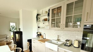Cozinha moderna com armários brancos, bancada de madeira, pia e fogão.
