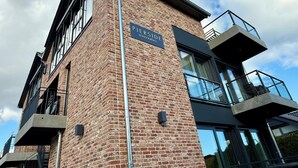 A modern building with a brick facade, a sign reading "PIERSIDE HAFKRUG," and a metal pole.