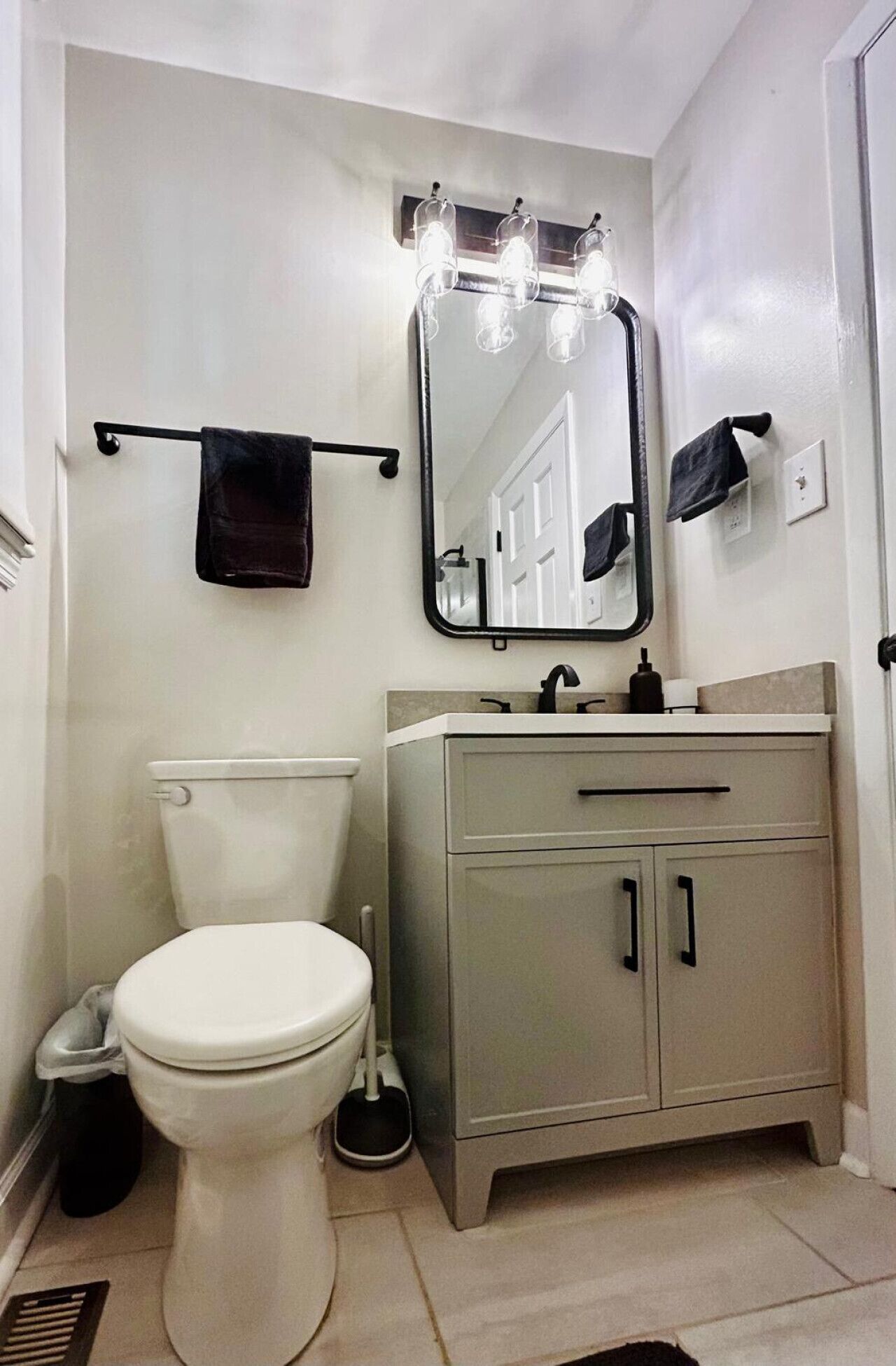 Een badkamer met toilet, wastafel, spiegel en handdoekhouder.
