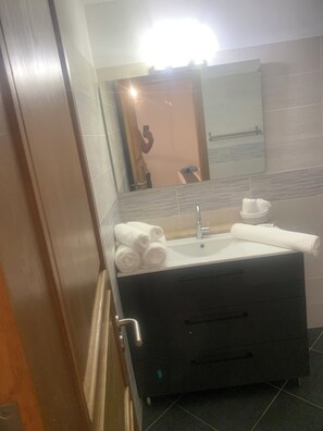 A bathroom with a dark-colored sink, a mirror, and a towel rack. - A Teghja (Figari)