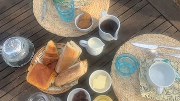 A table set with various food items and drinks, including bread, butter, jam, and coffee.