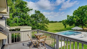 Eine Poolterrasse mit Holzstühlen und Blick auf eine grüne Landschaft.
