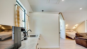 Ein modernes, kompaktes Zimmer mit Küchenzeile, zwei Betten und einem braunen Ledersofa.
