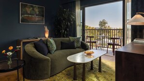 A modern living room with a green sofa, a white coffee table, and a balcony with a view. - Hotel Daphne (Houston)