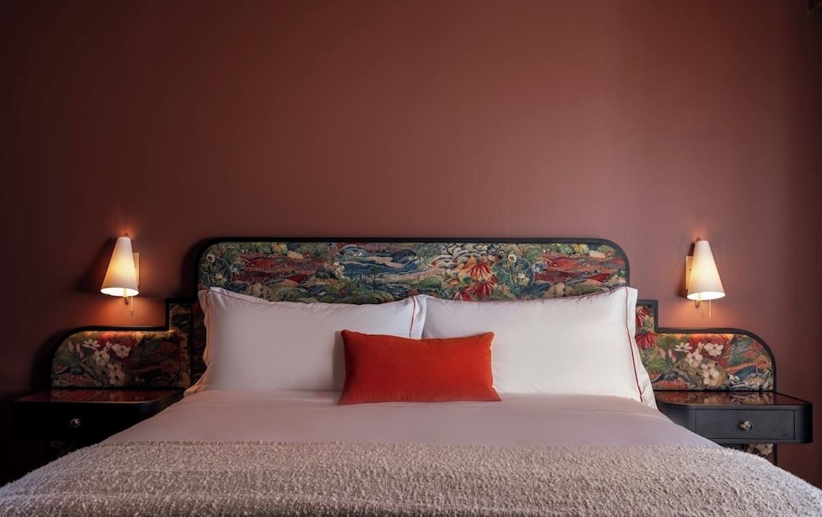 A bed with white and red pillows, a floral headboard, and two bedside lamps.
