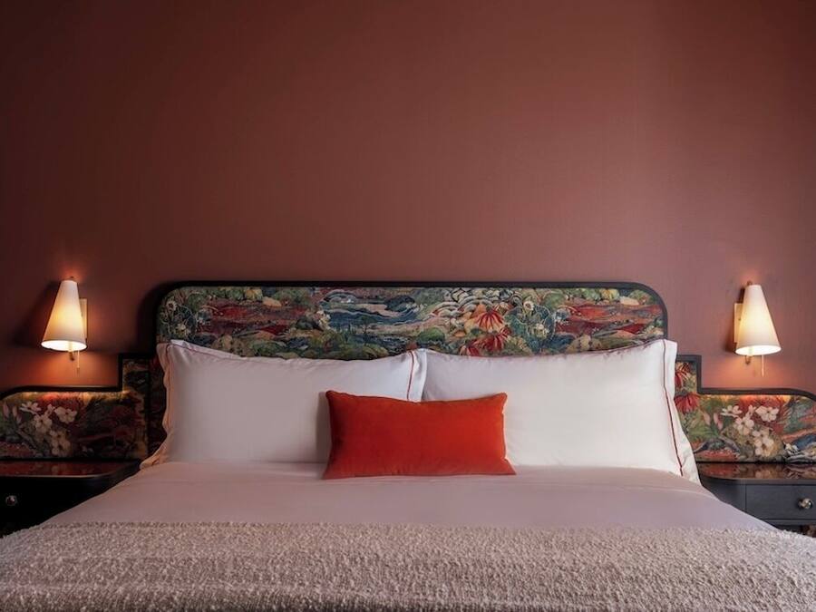 A bed with white and red pillows, a floral headboard, and two bedside lamps.