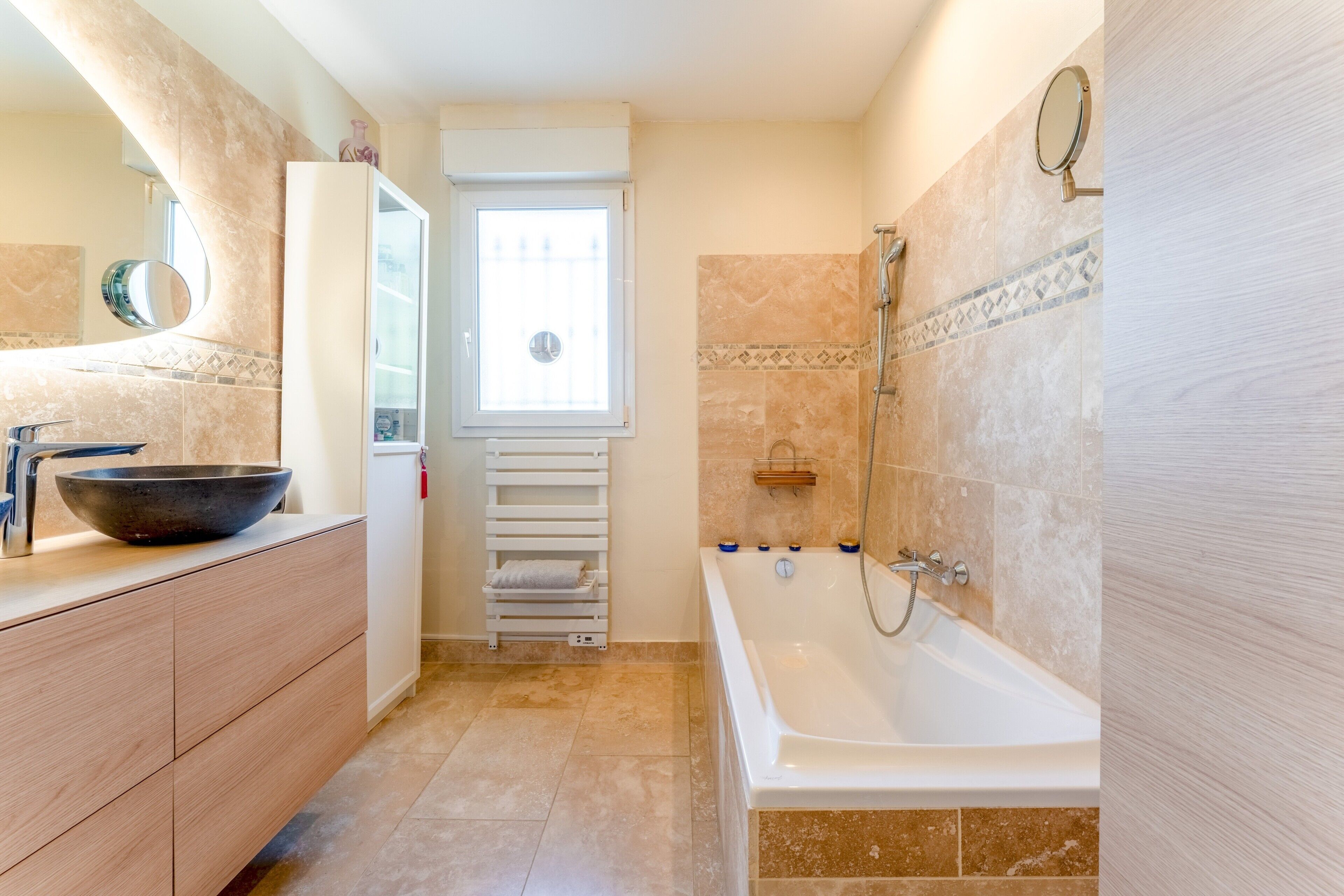 Ein modernes Badezimmer mit einer Badewanne, einem großen Spiegel und einem Fenster.