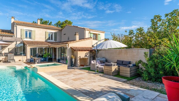 A swimming pool, outdoor furniture, and a house with a tiled roof.