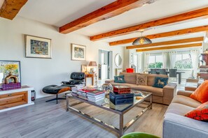 Amplia sala de estar con vigas de madera, un sofá, una mesa de centro y una estantería.