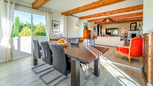 A modern kitchen with a TV, wooden beams, and a dining area with a table and chairs.