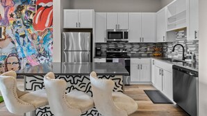 A modern kitchen with white cabinets, stainless steel appliances, and a black and white patterned table. - Modern 1BR Oasis – 8 mins to Downtown Nashville (Nashville)