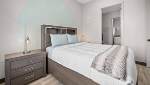 A modern bedroom with a bed, bedside tables, and a wardrobe. - Music On in Nashville - 8 min from Broadway! (Nashville)