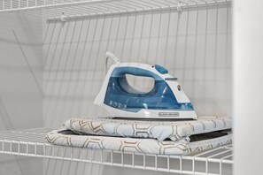 A white ironing board with a blue and white iron on top, in a room with a white tiled wall and a white ceiling. - 2BR Music Theme in Music City - 8min to Broadway (Nashville)