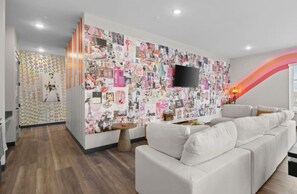A modern living room with a white sofa, a coffee table, and a wall covered with a collage of images.